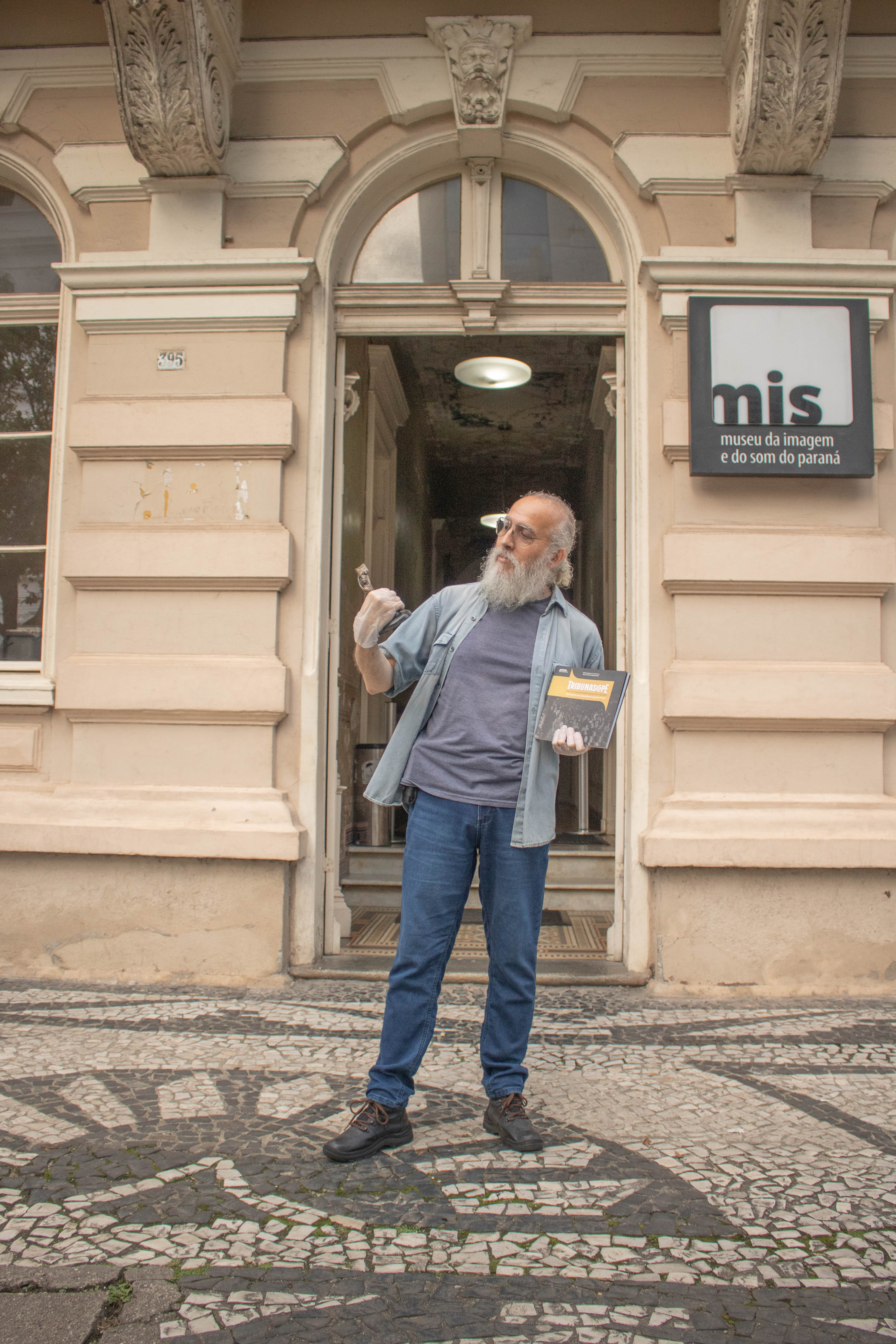 Autor do livro sobre o Tribunascope, Vidal Costa segura o troféu do festival de cinema curitibano em  frente ao Museu da Imagem e do Som do Paraná. Foto: Carlitos Marinho